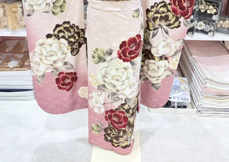 TKAZEN姫路店で人気のレトロ可愛い椿柄の振袖コーディネート。淡いピンクの振袖に赤い椿の花柄が華やかで、姫路の成人式におすすめの振袖スタイル。