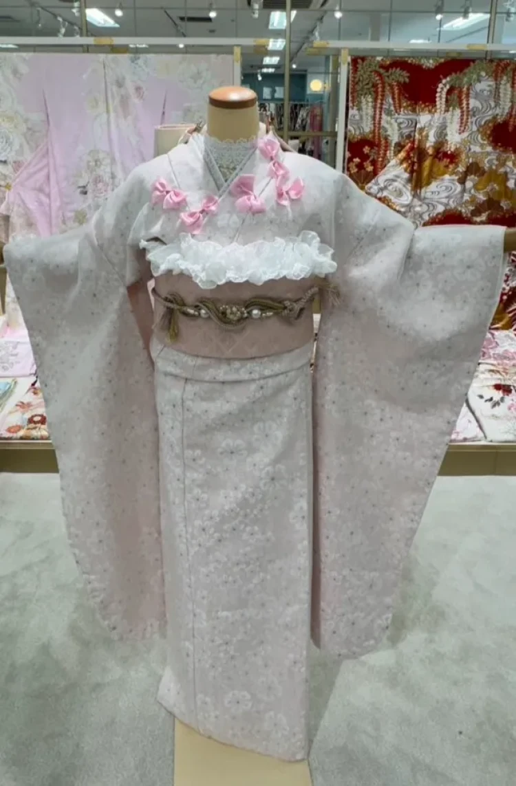 白地に淡い花柄の振袖にピンクのリボンとフリル帯を合わせたガーリーなコーディネート
