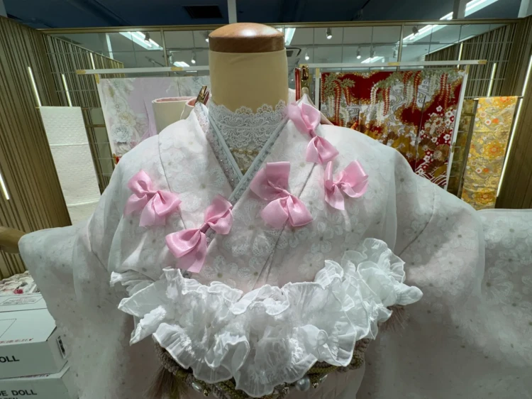 白地に淡い花柄の振袖にピンクのリボンとフリル帯を合わせたガーリーなコーディネート