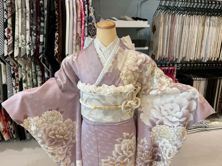 くすみピンクの地に大柄の牡丹や菊の花が描かれた上品な振袖に、アイボリーの帯を合わせたおすすめコーディネート。やわらかい色味と華やかな花柄が特徴で、卒業式や特別な日にぴったりの大人かわいいスタイル。