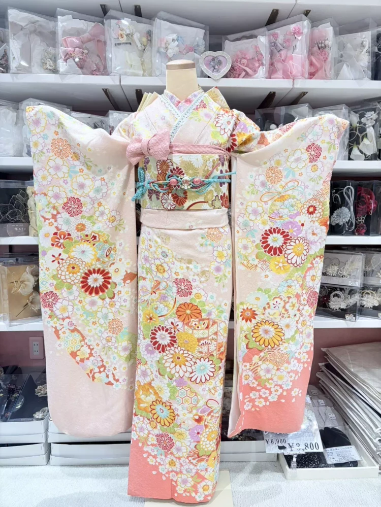 TAKAZEN姫路店の淡いサーモンピンクの可愛い古典柄振袖。桜や菊などが描かれたお振袖。