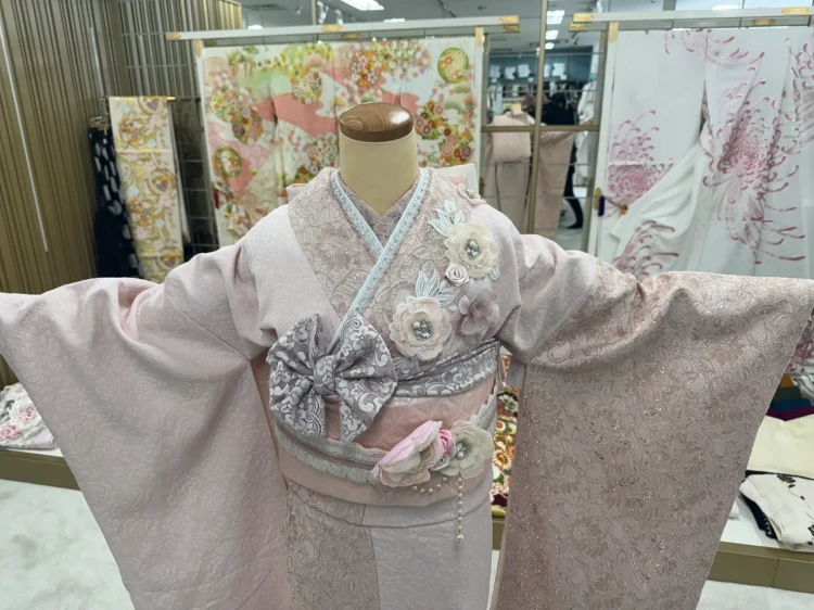 すみピンクの総レース振袖に立体フラワーをあしらったガーリーな振袖コーデ。リボン帯やレース小物を合わせた、トレンド感あふれるフェミニンスタイル。