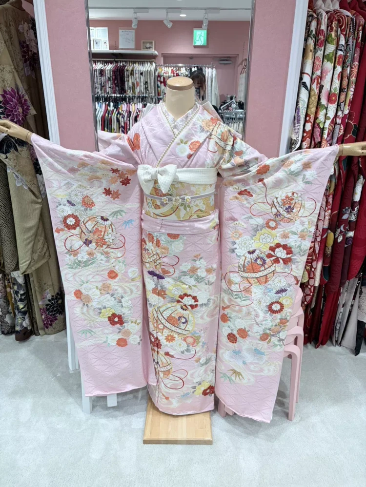 TAKAZEN姫路店の王道古典柄振袖。桜色のピンクカラーに花柄や大きな毬柄があしらわれたカワイイお振袖