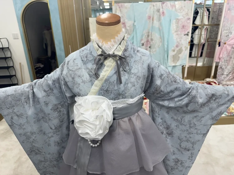 グレーのくすみカラー振袖にフリル袴を合わせた卒業式袴コーディネート。白いコサージュやフリル襟、リボンでガーリーに仕上げたトレンドスタイル。