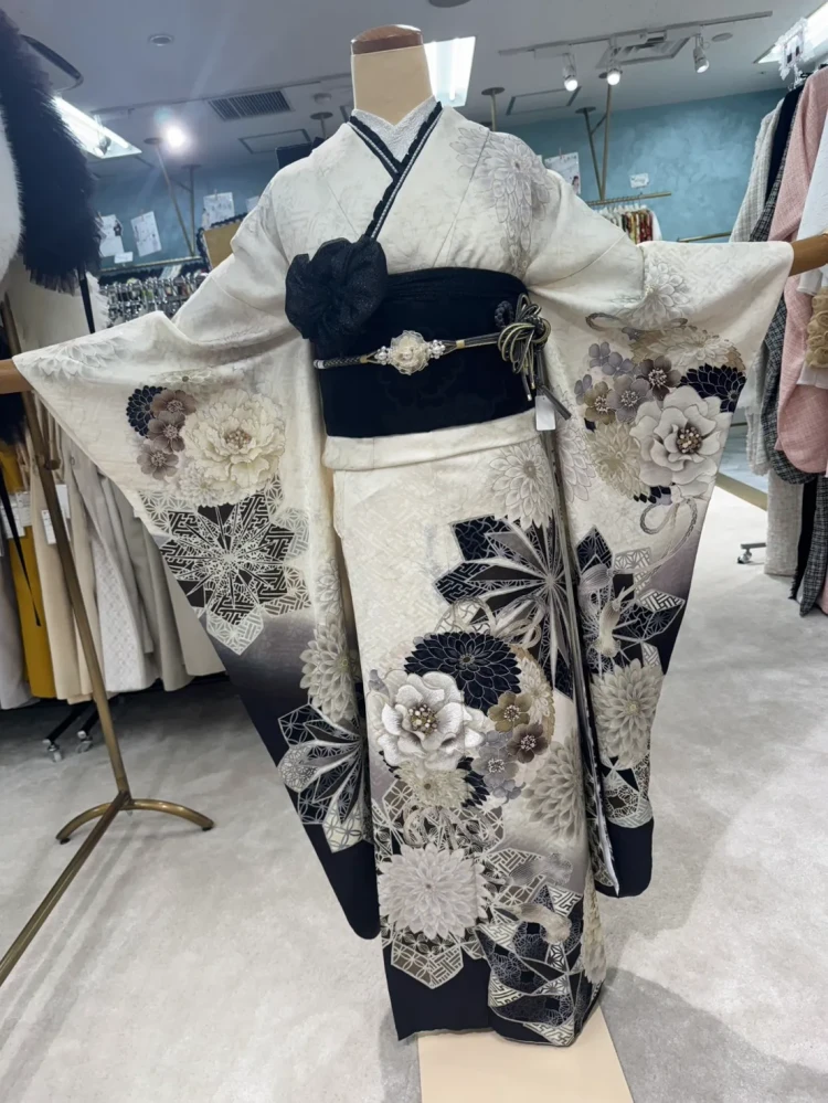 白地に黒とグレーの花柄が華やかに描かれた振袖。黒の帯と帯締めを合わせた上品でモダンな振袖コーデ