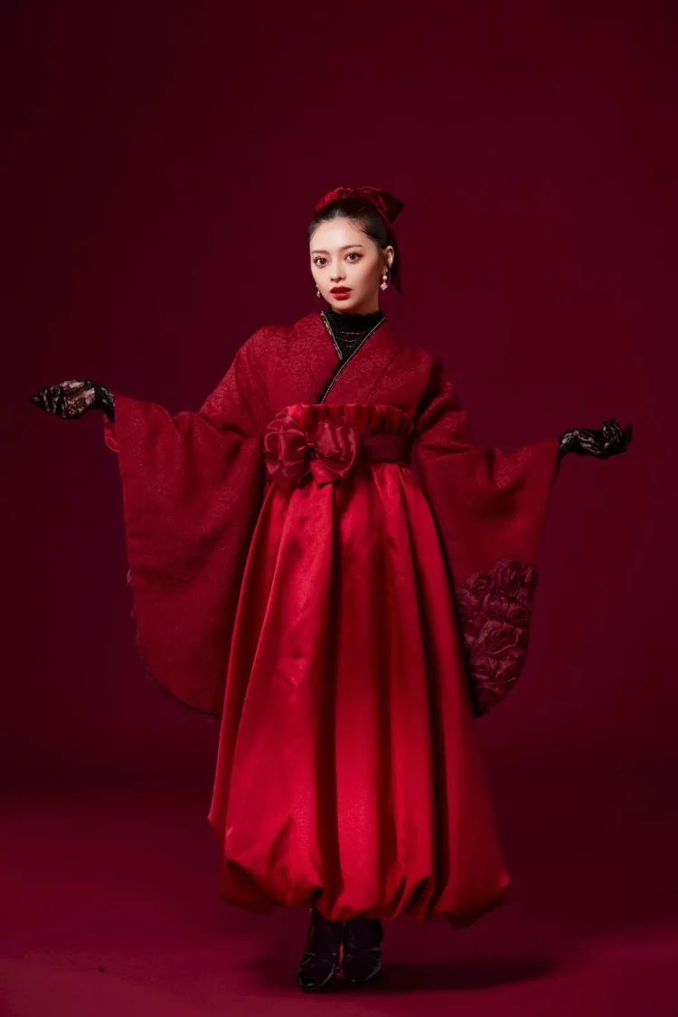 深みのある赤の着物とブラックの袴を組み合わせた、個性的で華やかな卒業式袴コーデ。大きなリボンやレースグローブを取り入れた存在感のあるスタイル。