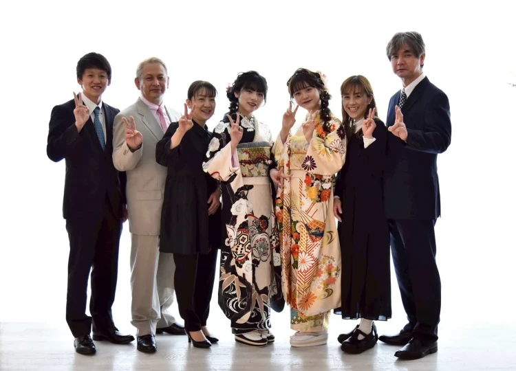 振袖姿のお嬢様2人とご家族が並んで撮影した家族写真。みんなでピースサインをして、笑顔いっぱいの楽しい雰囲気が伝わる前撮り写真。