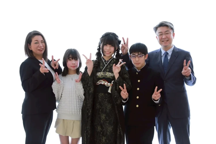 黒の振袖姿のお嬢様を中心に、ご家族と一緒に撮影した記念写真。みんなでピースサインをしながら、和やかで楽しそうな雰囲気の前撮り写真。