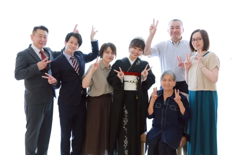 黒の振袖姿のお嬢様を中心に、ご家族みんなで撮影した集合写真。世代を超えて集まり、ピースサインで楽しそうに撮影した家族写真。