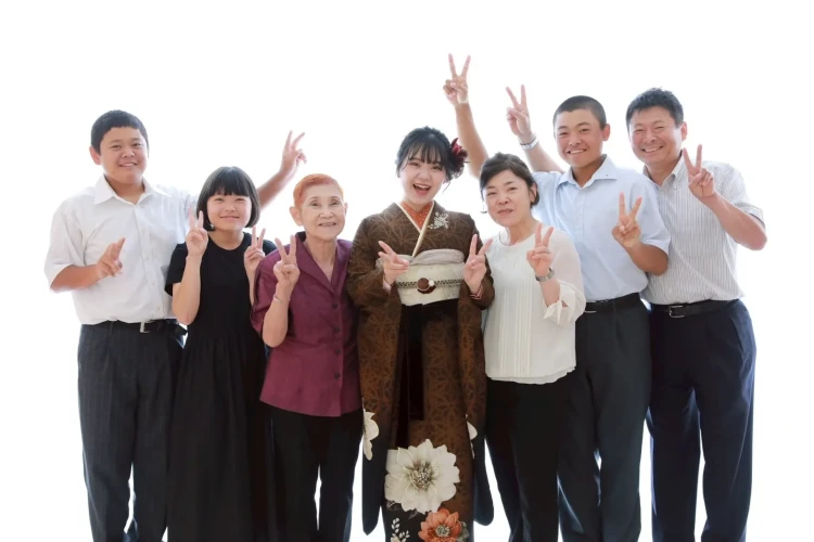 ブラウン系の振袖姿のお嬢様を中心に、祖母やご家族と一緒に撮影した集合写真。みんなでピースサインをしながら笑顔で残した、温かな家族写真。