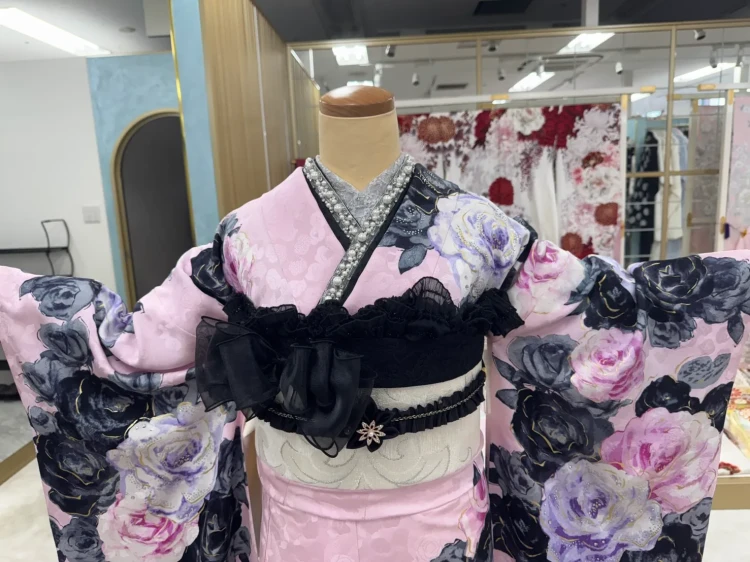 ピンク地に黒やネイビー、紫、白のバラ柄が華やかな振袖の全身コーディネート。黒のフリル帯とリボン、パールの重ね衿を合わせた大人かわいいゴシックスタイル。
